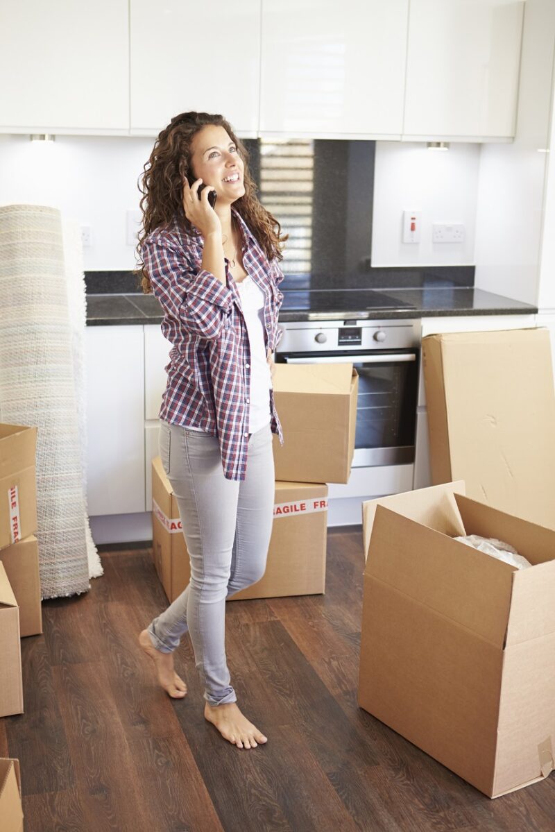 Woman Moving Into New Home Talking On Mobile Phone